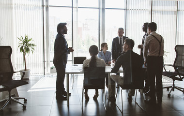 Silhouettes of people sitting at the table. A team of young businessmen working and communicating...