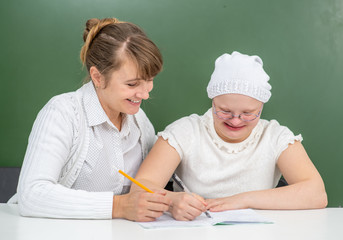 Teacher helps to young girl with Down Syndrome at school