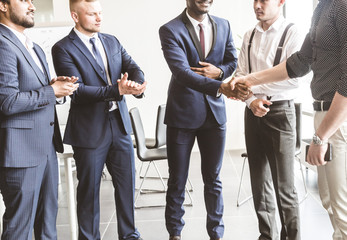 A team of young businessmen working and communicating together in an office. Corporate businessteam and manager in a meeting. handshake