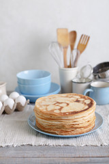 Cooking pancakes. Shrovetide (Maslenitsa) - blini stack on a blue plate on a wooden table.