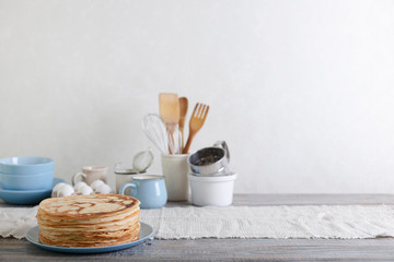 Cooking pancakes. Shrovetide (Maslenitsa) - blini stack on a blue plate on a wooden table.