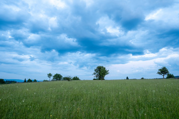Obraz premium The colors of the sky after sunset with clouds above the mountain meadow.