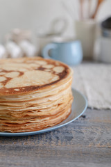 Cooking pancakes. Shrovetide (Maslenitsa) - blini stack on a blue plate on a wooden table.
