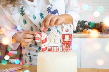 Cake decoration female hands in the frame in the bright kitchen gingerbread houses Christmas treat for the holiday lights of garlands