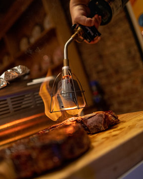 A home chef uses a blowtorch to sear a prime cut of steak