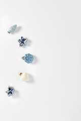 Christmas decor in the form of cones, hearts, and stars in blue on a white background. minimalistic holiday concept. flat lay, vertical frame, copy space