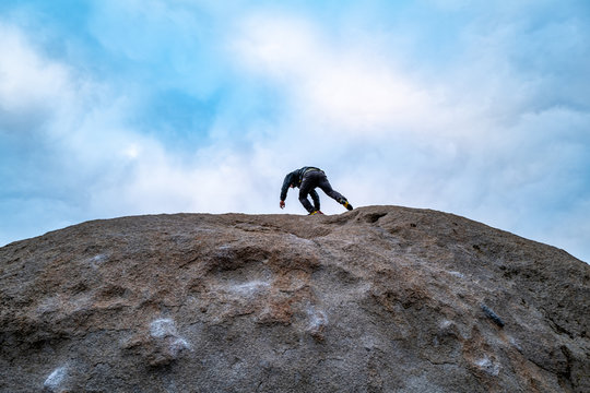 A rock climber tops out a boulder problem in Bishop, California