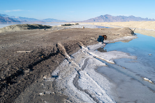 A young woman walks carefully on a salt pan in the middle of nowhere