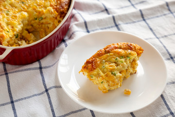 Homemade Cheddar Corn Pudding Casserole on a white plate, side view. Close-up.