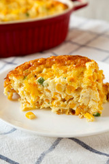 Homemade Cheddar Corn Pudding Casserole on a white plate, side view. Close-up.