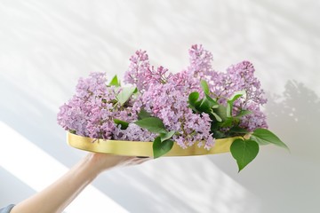 Floral decor of interiors, lilac flowers in form of bouquet on round golden tray