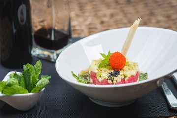 Classic traditional tartar salad laid in a round shape, stylish serving in an oriental style table in a restaurant. Tasty and healthy food. Guests service. Tar tar on a stylish plate with decor.