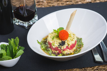 Classic traditional tartar salad laid in a round shape, stylish serving in an oriental style table in a restaurant. Tasty and healthy food. Guests service. Tar tar on a stylish plate with decor.
