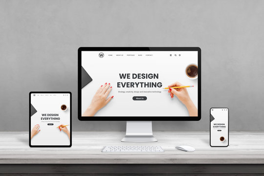 Web design studio with multiple devices on office desk. Concept of responsive, flat web page design. Modern devices with thin edges on wooden desk