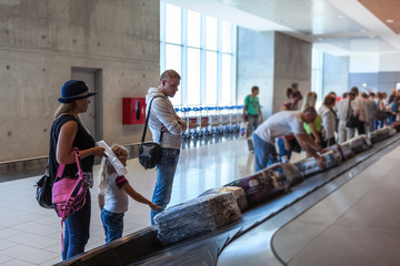 Family waiting their suitcase on baggage carousel in airport terminal