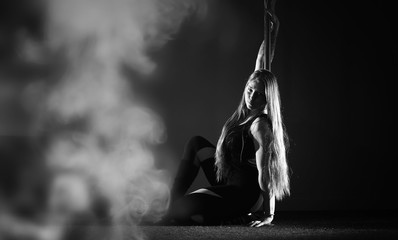 The dancer on the pylon in the studio. Girl doing exercises on a sports equipment.