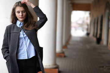 Young beautiful girl on a walk near building with a column