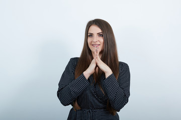 Cheerful young caucasian lady over isolated gray background wearing casual black dress with white polka dot, keeping hands together, smiling. People lifestyle concepte.