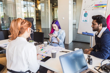 Group of multi ethnic executives discussing during a meeting. Business man and woman sitting around table at office and smiling. A team of young creative designers