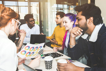 Group of multi ethnic executives discussing during a meeting. Business man and woman sitting around table at office and smiling. A team of young creative designers