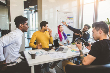 Group of multi ethnic executives discussing during a meeting. Business man and woman sitting around table at office and smiling. A team of young creative designers