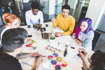 Group of multi ethnic executives discussing during a meeting. Business man and woman sitting around table at office and smiling. A team of young creative designers