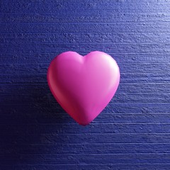 Pink heart shape on blue wooden background.