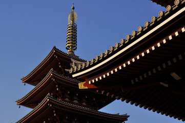 Fototapeta na wymiar edge of a temple roof and pagoda in a japanese buddhist temple on a clear blue sky