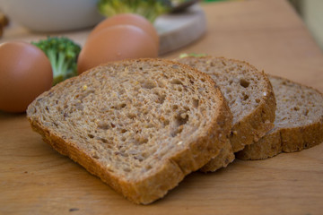 Close-up of healthy vegetarian food, vegetables - green broccoli, bread, eggs and onions in the kitchen placed on wooden table 