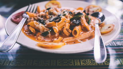 A dish of the paste with seafood and vegetables in a red sauce. Close up.