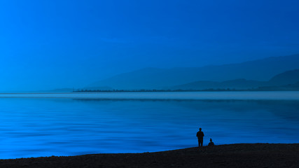 Fototapeta na wymiar Seascape blue evening and silhouettes of people .