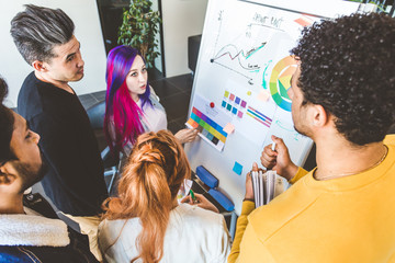 Group of multi ethnic executives discussing during a meeting. Business man and woman sitting around table at office and smiling. A team of young creative designers