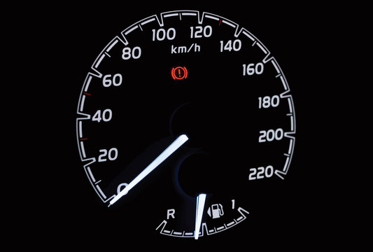 Illustration of side view of modern car dashboard with speedometer, fuel gauge indicator and handbrake warning light sign. Close up of low petrol level showing on car instrument panel.