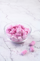 Pink Marshmallows in a glass transparent bowl, on a light marble table.