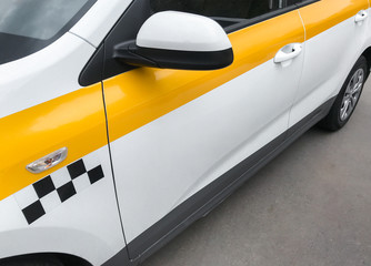 Close up side view of  yellow and white taxi car with checker