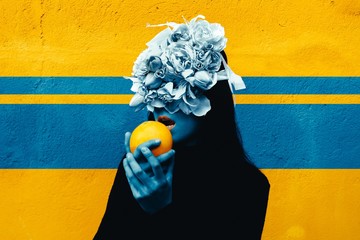 Female hand holding orange. Portrait Of Young Girl standing on color  background