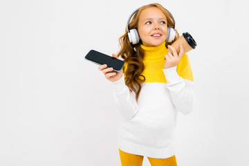 Beautiful teenager caucasian girl listen to music with big earphones and drinks coffee isolated on white background