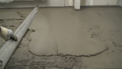 Laying self-leveling floor screed and uniformly spreading with a tool. Leveling the uneven floor....