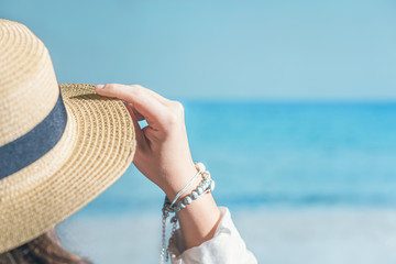 Woman in a straw on a beach with sea view.