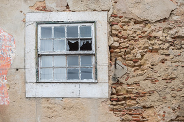 old crumbly wall with flaking plaster and broken window, abandoned house