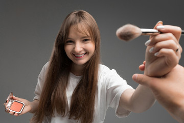 caucasian beautiful girl in a white t-shirt holds out a makeup brush on a dark background