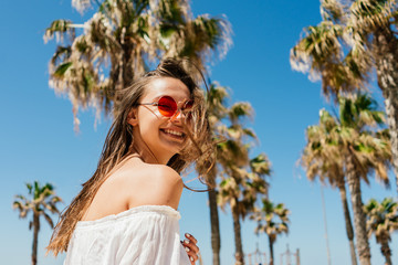 laughing infectiously a beautiful girl looks over her naked shoulder against a background of palm trees and sky