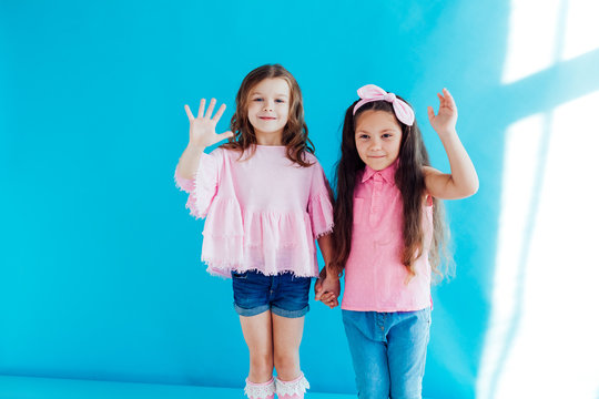 two little girls girlfriends sisters portrait on a blue background