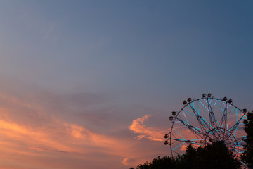 Silhouette of ferris wheel at sunset at county fair.