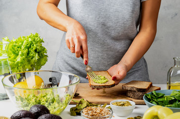 Woman spreads avocado guacamole on bread. healthy food concept.