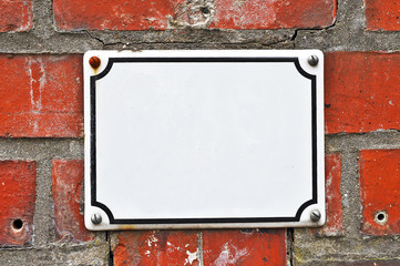 A white colored house number plaque, fixed on a brick wall, without number. Mock up/ template for designers