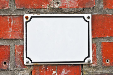 A white colored house number plaque, fixed on a brick wall, without number. Mock up/ template for...