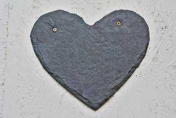 A grey, hear shaped house number plaque, fixed on a wall, without number. Mock up/ template for...