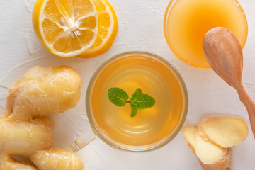 Tea with ginger, mint, lemon and honey on a white wooden table. Close-up. Top view