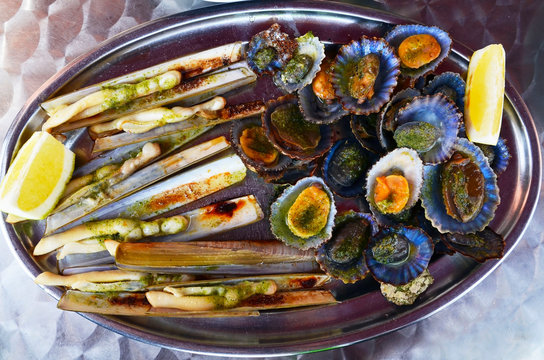 Grilled limpets served with lemon.Razor shells or navajas and lapas grelhadas on a metal plate.Traditional dish of Portugal and a typical snack of the Canary Islands.Seafood concept.Selective focus.